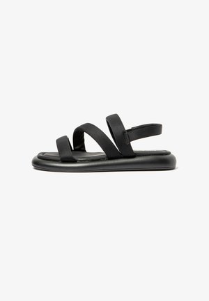 Black sandals with a flat sole, featuring two wide, soft straps and a narrow heel strap for secure fit. Smooth material with no patterns.
