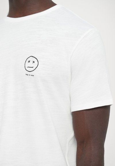 White short-sleeve t-shirt in a lightweight fabric with a small black embroidered face logo and brand text on the chest.