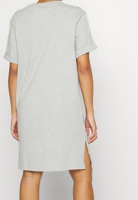 Grå bomulls T-shirt klänning med uppvikta ärmar, sidofickor och en avslappnad passform, med en enkel design utan mönster eller detaljer.