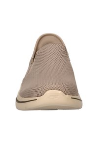 Lichtbruine instapper met een ademende bovenkant van mesh en een gestructureerde afwerking. Heeft een rubberen zool met een subtiele accentlijn.