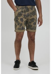 Șorturi khaki cu un model tropical de frunze verzi închise. Au un brâu elastic, șnur de ajustare și mansete răsucite. Purtați cu adidași negri.