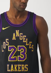 Čierny basketbalový dres s fialovými a žltými akcentmi. Obsahuje texty "LOS ANGELES" a "LAKERS" a veľké číslo "23", vyrobený z priedušnej sieťoviny.