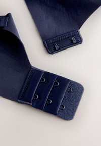 Tengerészkék színű szövetruha állítható horog- és szemzárral. Sima textúrájú és lekerekített szélekkel; több rögzítési lehetőséget tartalmaz.