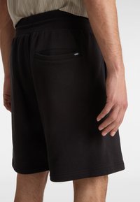Pantaloni corti neri in cotone con vita elasticizzata, dotati di una tasca posteriore e un discreto logo del marchio. Texture liscia e vestibilità casual.