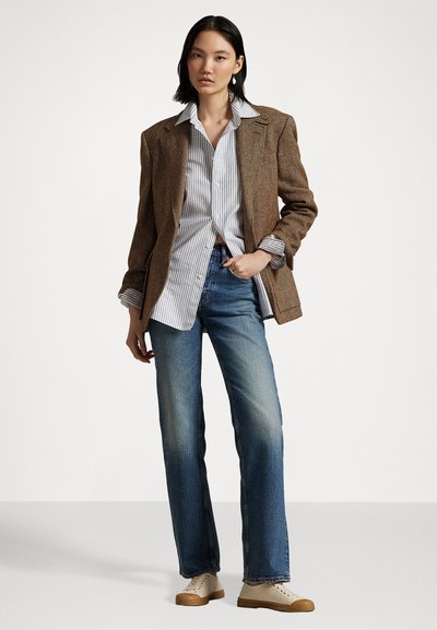 Braun gemusterter Blazer im Fischgrätenmuster, weißes gestreiftes Hemd, blaue gerade Jeans und cremefarbene Sneakers mit strukturiertem Sohlen. Minimalistische Designdetails.