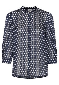 Blouse en voile bleu marine avec des pois blancs, col rond, fermeture à boutons et manches longues bouffantes. Présente des plis verticaux et un ourlet arrondi.