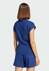 Top sportivo blu navy a maniche corte con design aderente, abbinato a pantaloni corti coordinati. Il materiale in misto cotone offre una texture morbida.
