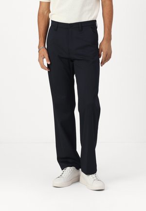Donkerblauwe broek gemaakt van zachte stof, met een recht gesneden ontwerp, achterzakken en een knoopsluiting bij de taille.