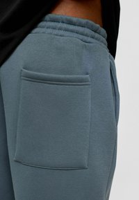 Lichtblauwe sweatpants met een zachte textuur, voorzien van een elastische tailleband en een patchzak aan de zijkant.