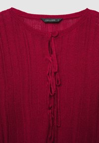 Rotes Strickoberteil mit gerippter Struktur, Rundhalsausschnitt und Bindeband vorne. Markenetikett "Calliope" sichtbar. Größe S.