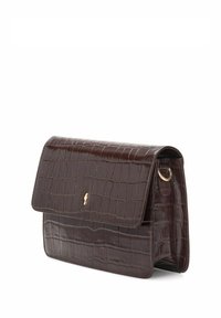 Torebka ze skóry w ciemnym brązowym kolorze z wzorem krokodyla, zamykana na klapę, z małym złotym emblematem z przodu, metalowym pierścieniem po boku do przypięcia paska.