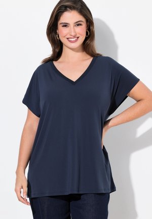 Donkerblauw T-shirt met korte mouwen en V-hals, met een zachte textuur en een subtiele glinsterende afwerking langs de halslijn. Losse pasvorm met zijsplitten.