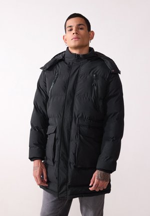 Chaqueta de plumas negra con cuello alto, cierre de cremallera y botones a presión, dos bolsillos frontales y capucha. Presenta una textura acolchada y un color sólido.