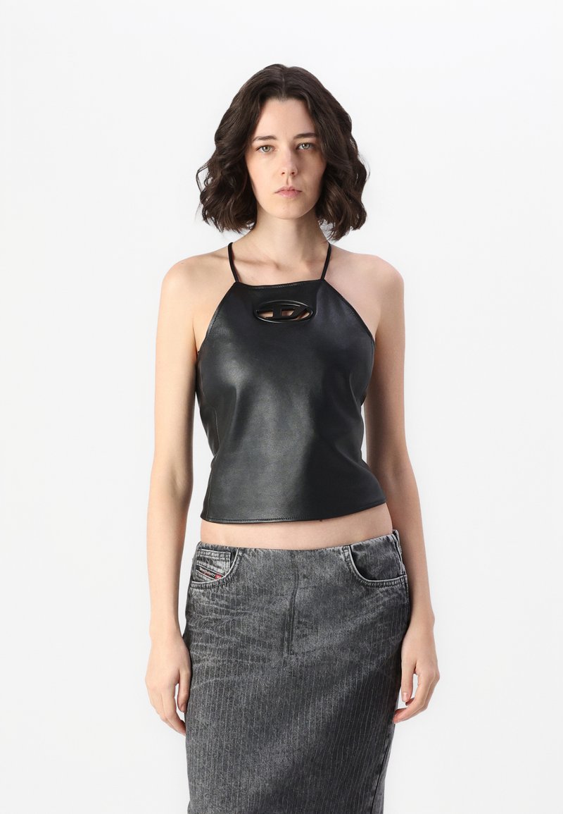 Top halter in pelle nera con un'apertura a chiave, caratterizzato da spalline sottili e un design aderente. Abbinato a una gonna di jeans grigia a righe.