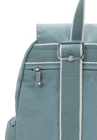 Zaino azzurro chiaro realizzato in tessuto testurizzato, con zip argento e dettagli sulle cinghie, cuciture bianche e un design semplice.