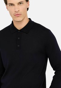 Polo a maniche lunghe di colore blu navy, realizzato in tessuto morbido, con colletto classico e design a tre bottoni.