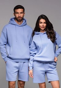 Sweatshirts bleu clair et shorts assortis en tissu doux. Les sweatshirts sont dotés de cordons de serrage, tandis que les shorts possèdent des poches.