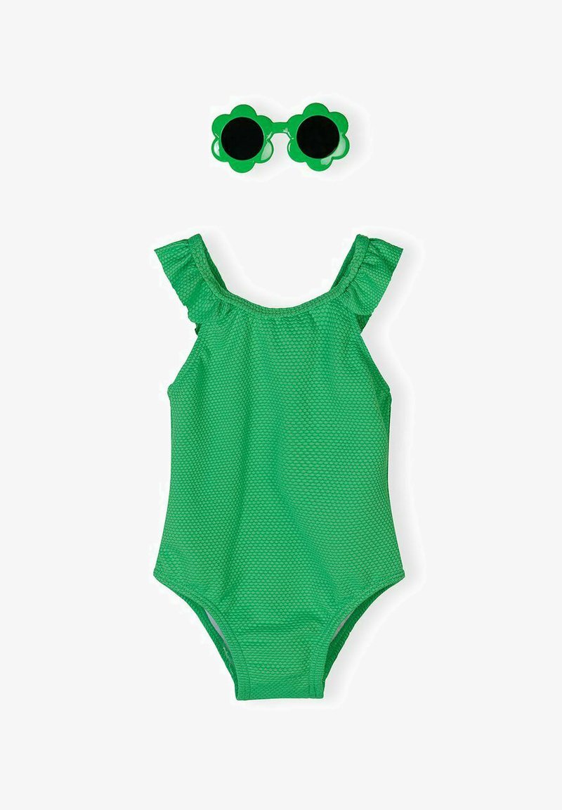 Maillot de bain une pièce vert texturé avec bretelles volantées aux épaules et lunettes de soleil vertes assorties en forme de fleur.
