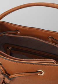 Borsa a mano in pelle marrone con superficie testurizzata, dotata di hardware dorato, chiusura a coulisse e più scomparti interni.