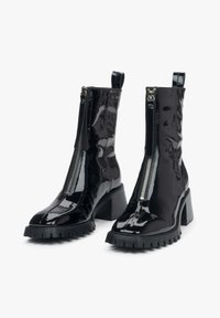 Zwarte patenten enkelboots met een chunky hak, ritssluiting, textuur bovenwerk en robuute zool. Voorzien van een haakje op de kraag voor gemakkelijk aantrekken.
