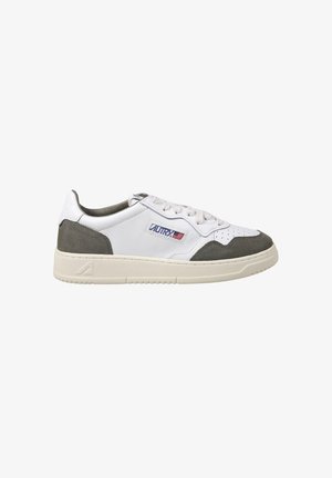 Zapatilla deportiva baja blanca y gris con cierre de cordones, puntera perforada, suela crema y logo de Autry con bandera americana en el lateral.