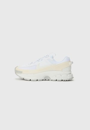 Baskets avec une tige en mesh blanc, des accents crème et une semelle épaisse et texturée. Équipées de lacets et d'un talon renforcé pour un meilleur maintien.