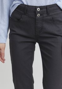 Zwarte jeans met een dubbele knoopsluiting, voorzakken en een recht model. Het materiaal is een gladde denim met een lichte glans.