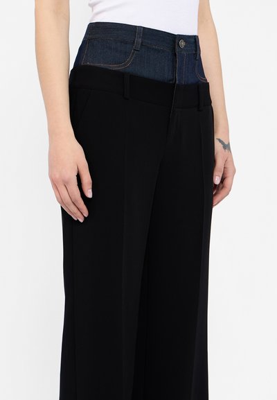 Wide-leg black pants featuring a denim waistband with a button and pocket details. Fabric appears smooth with a contrast texture at the top.