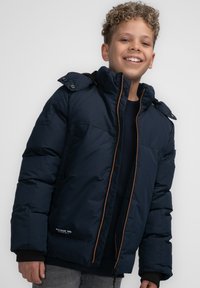 Marineblauer Steppjacke mit hohem Kragen, orangefarbenem Reißverschlussdetail, Schulterknöpfen und sichtbarem Logo am unteren Saum.
