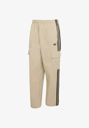 Beżowe spodnie typu cargo z elastycznym pasem, bocznymi kieszeniami oraz czarnymi pionowymi paskami. Na froncie znajduje się logo Adidas.