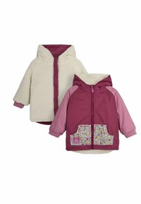 Två jackor: en krämfärgad fuskpäls med huva och en mörkrosa med blommiga fickdetaljer, båda med dragkedjor och elastiska muddar.