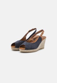 Dark blue suede wedge sandals with open toes, tan leather accents, and textured beige woven platform. Adjustable ankle strap with buckle.