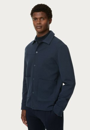 Marineblaue Baumwolljacke mit Druckknopfverschluss, Kragen und zwei vorderen Taschen, die eine glatte Textur und ein einfaches Design aufweist.