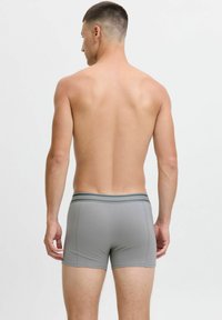 Boxer shorts de algodón gris con un diseño ajustado, que presentan una cinturilla en contraste con acentos verdes, mostrados desde la parte trasera sobre un fondo neutro.