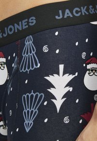Mornarčaste bokserice s crnim elastičnim pojasom na kojem je natpis "JACK & JONES", ukrašene bijelim i svijetloplave boje božićnim uzorcima.