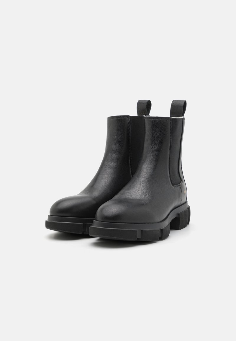 Schwarze Chelsea-Stiefel aus Leder mit glatter Oberfläche, elastischen Seitenteilen und einer klobigen schwarzen Gummisohle sowie Zugschlaufen für ein einfaches Anziehen.