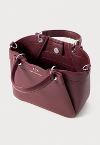 Sac fourre-tout en cuir bordeaux avec deux poignées, quincaillerie en argent, accents circulaires et fermeture à pression intérieure. Extérieur texturé avec un logo subtil.