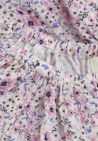 Bloemenstof met roze, paarse en zwarte bloemen op een lichte achtergrond. Verzamelde taille met elastische details, zachte en gestructureerde oppervlakte.