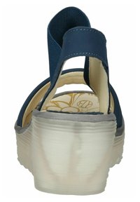 Sandalias de tela azules con suela gris, que cuentan con una correa ancha, parte trasera abierta y plantilla con un patrón. Superficie texturizada y diseño estructurado.