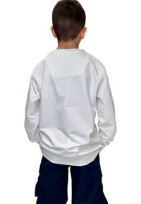 Camicia bianca a maniche lunghe con collo tondo e design semplice, realizzata in tessuto morbido e liscio. La vista posteriore presenta dettagli minimi.