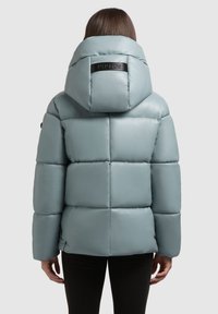 Chaqueta acolchada verde menta con un alto cuello y un parche de logo en la parte posterior. Presenta paneles cosidos y una textura suave y brillante.