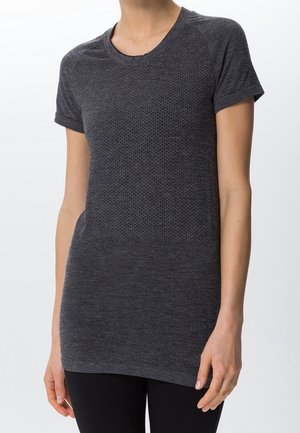 Woman wearing a dark gray short-sleeve, textured fitted T-shirt and black pants, standing with arms relaxed by her sides.