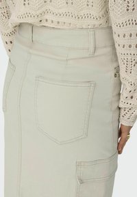 Helles beiges Denim-Rock mit zwei Gesäßtaschen und Seitentaschen-Details. Verfügt über dezente Nähte und eine glatte Textur.