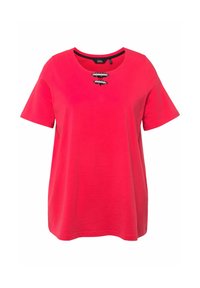 Camiseta roja de manga corta y escote redondo, con tres anillas metálicas en el centro frontal. Fabricada en tela suave.