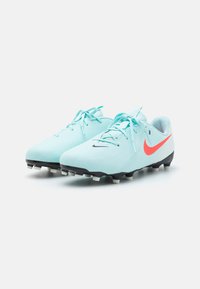 Vaaleansiniset jalkapallokengät, joissa on tyylikäs muotoilu, musta ulkopohja ja valkoiset nupit, sekä näyttävä oranssi Nike Swoosh -logo.