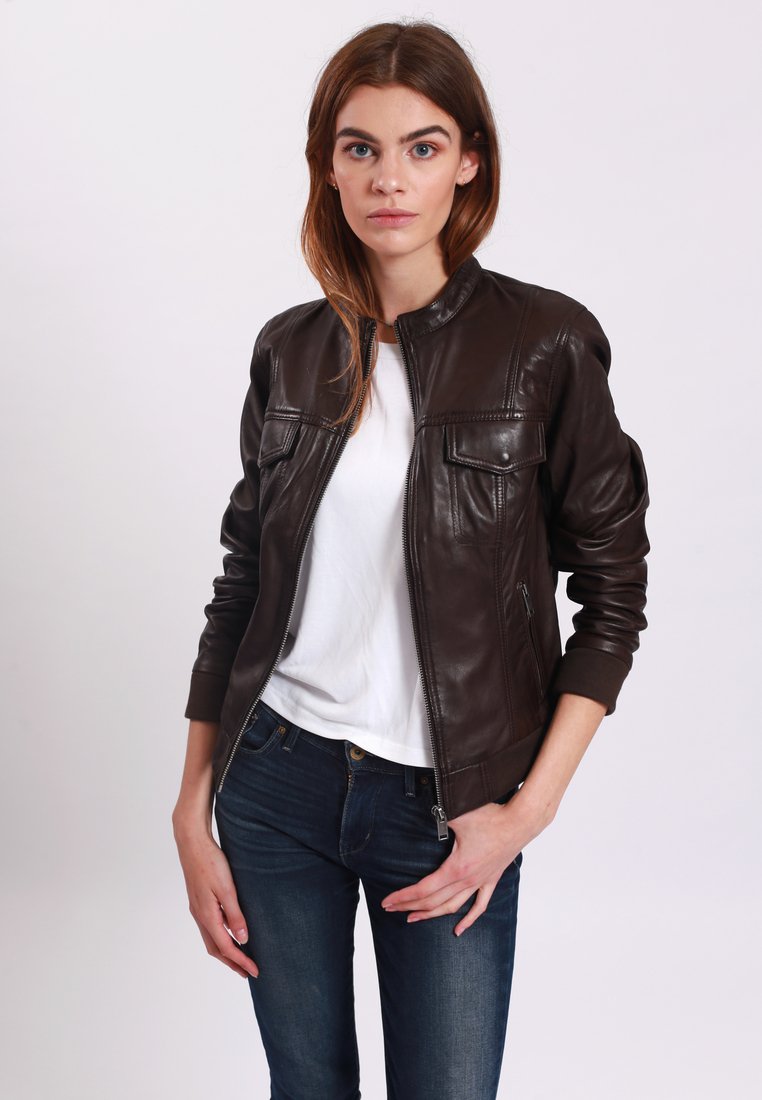 Giubbotto bomber in pelle marrone con zip frontale, polsini a coste e due tasche frontali. Indossato sopra una t-shirt bianca e jeans blu.