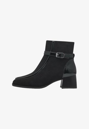 Botines negros con parte superior de ante, acentos de charol brillante, una correa plana con un broche de metal y un tacón grueso.