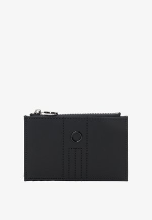 Musta lompakko, valmistettu sileästä nahasta, jossa on vetoketjusuljin, pyöreä metallikoriste ja hienovaraiset ompeleet edessä.