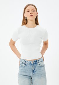 Witte geribde short-sleeve fitted top met een ronde halslijn, gecombineerd met lichtblauwe high-waisted jeans met klassieke zakken en een knop.