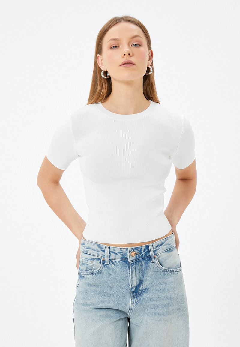 Witte geribde short-sleeve fitted top met een ronde halslijn, gecombineerd met lichtblauwe high-waisted jeans met klassieke zakken en een knop.